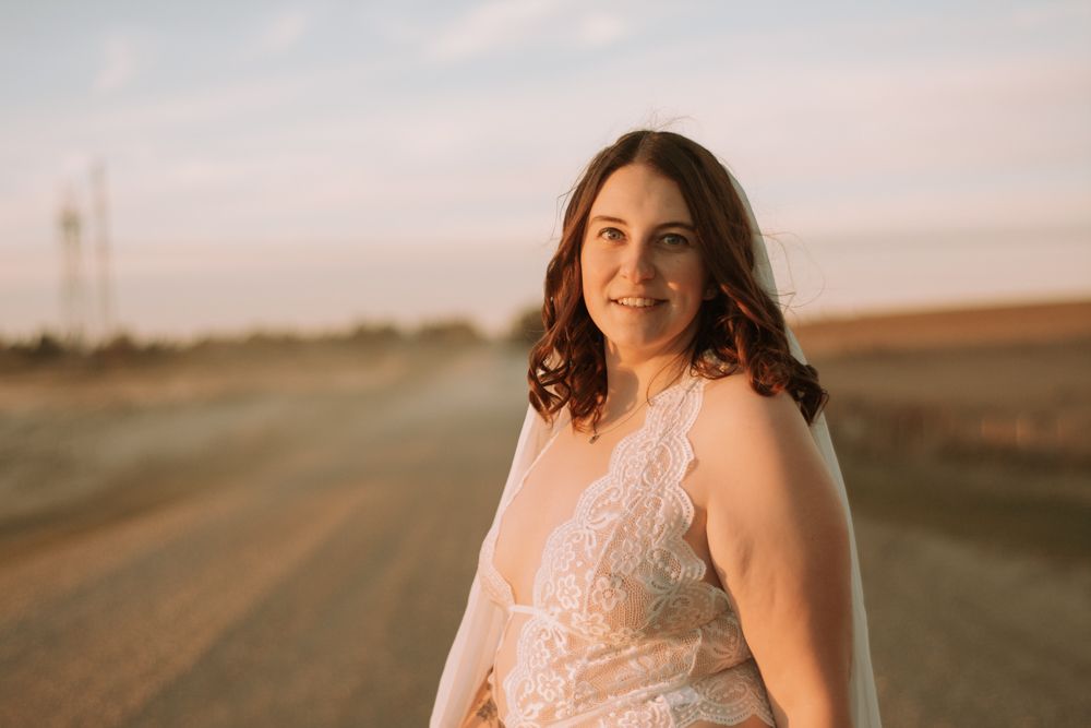 Candid portrait on a country road during sunset with soft pink sky in background.
