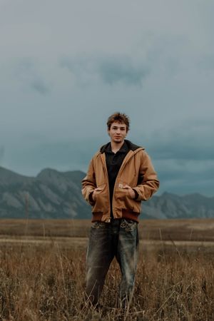 Boy stands and poses for senior photos, cinematic, mountain, and portrait photos in Boulder, Colorado outside and in nature