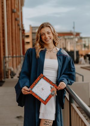 Girl stands with her cap and poses for graduation photos, cinematic photos, and portraits in Denver, Colorado outside and in nature