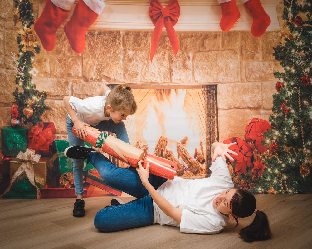 Awkward family photo of mum and daughter pulling an oversized christmas bon bon or cracker