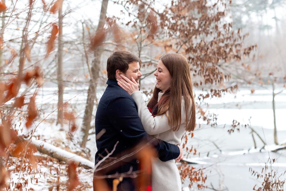 Romantic couple embracing among frost-covered branches in a winter forest.