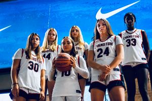 Six Evanston basketball players in white uniforms pose confidently in front of a Nike backdrop.