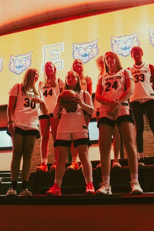 Evanston girls basketball team poses in white uniforms on court, players wearing numbers 30, 44, 18, 24, and 33.