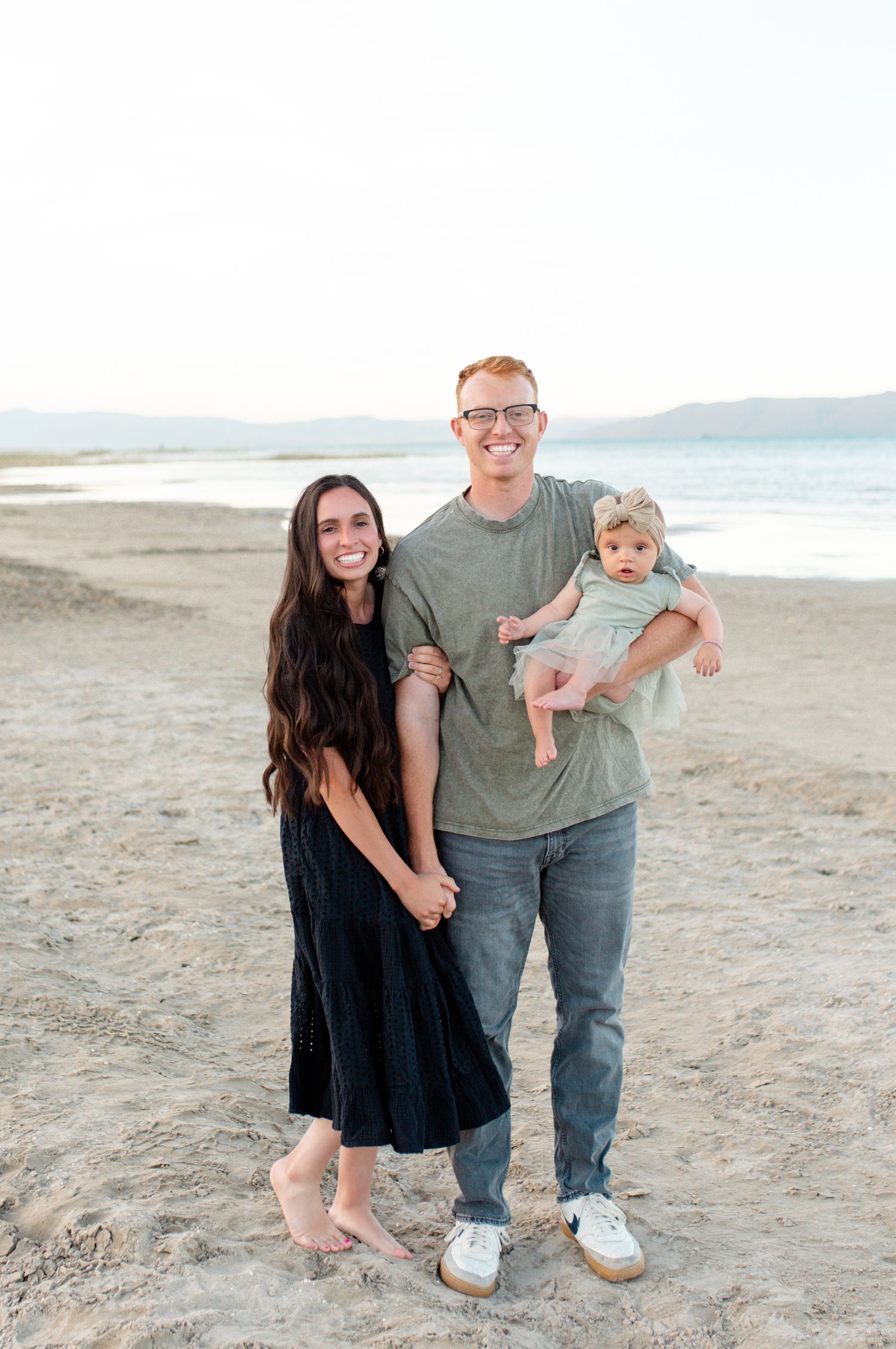 Maile Rupe, an O'Fallon MO family photographer, smiling outdoors with her husband and baby daughter.