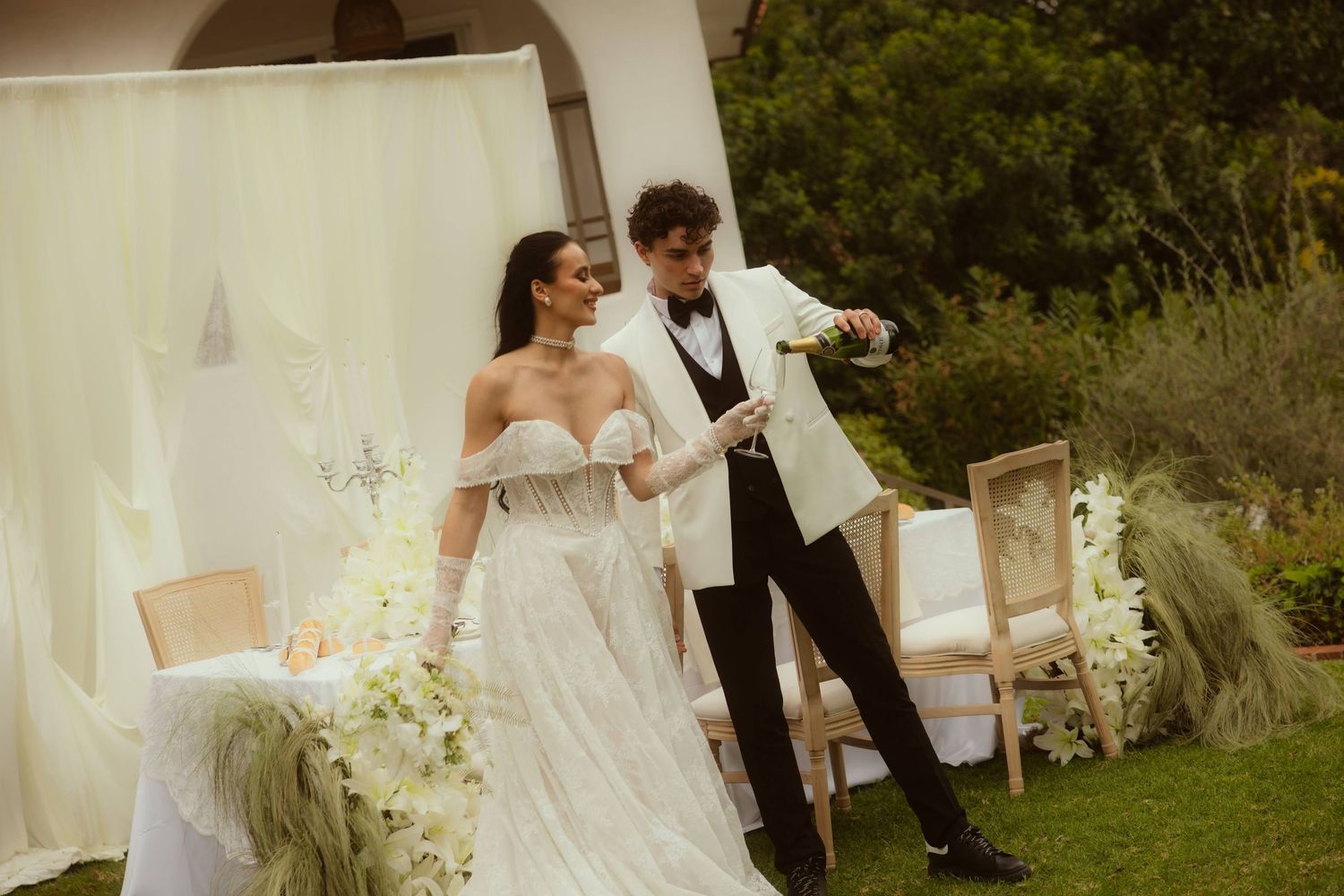 Bride and groom pouring champagne outdoors at elegant wedding reception after their Ojai elopement.