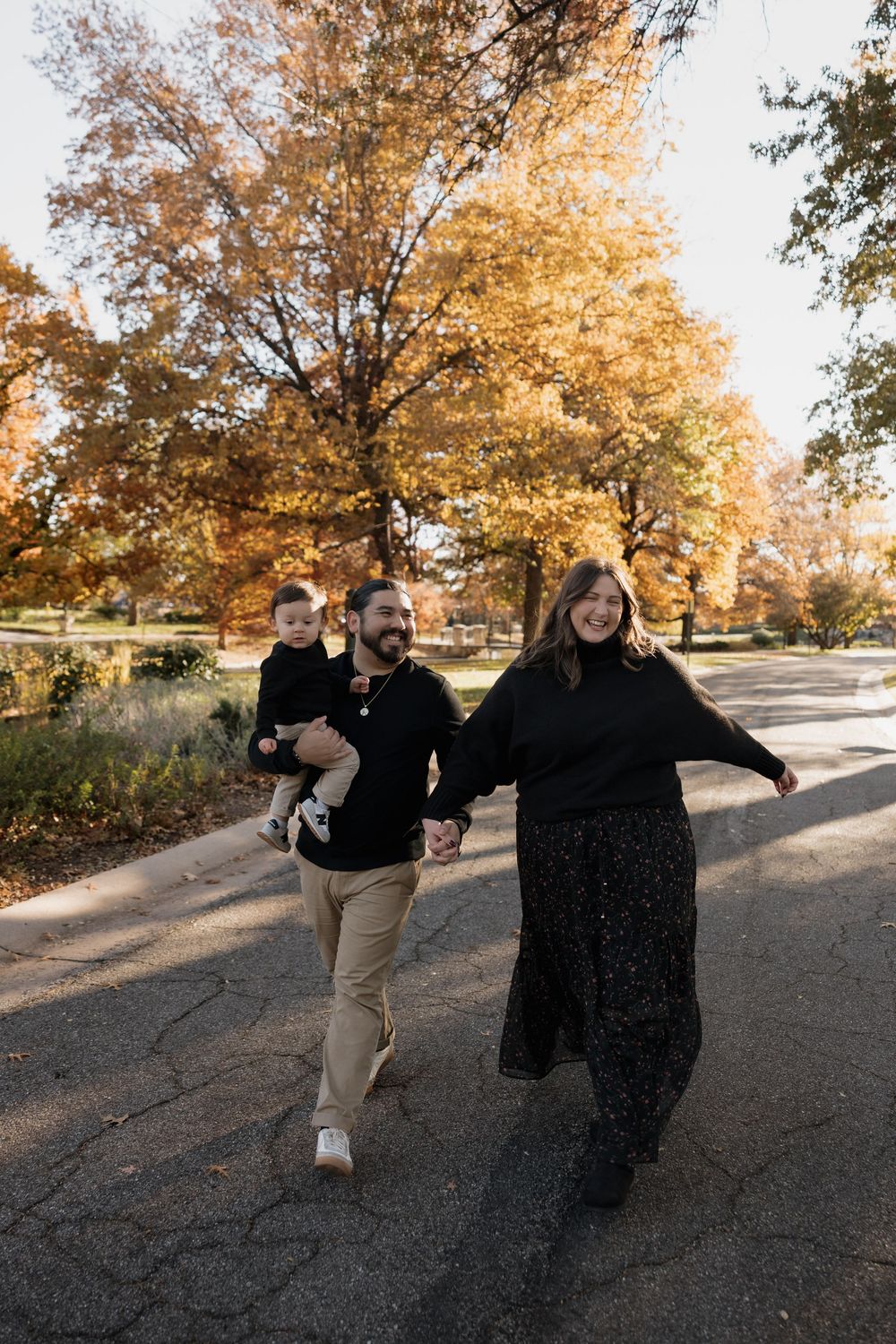 Happy family walking together on a path surrounded by vibrant autumn foliage in a park.