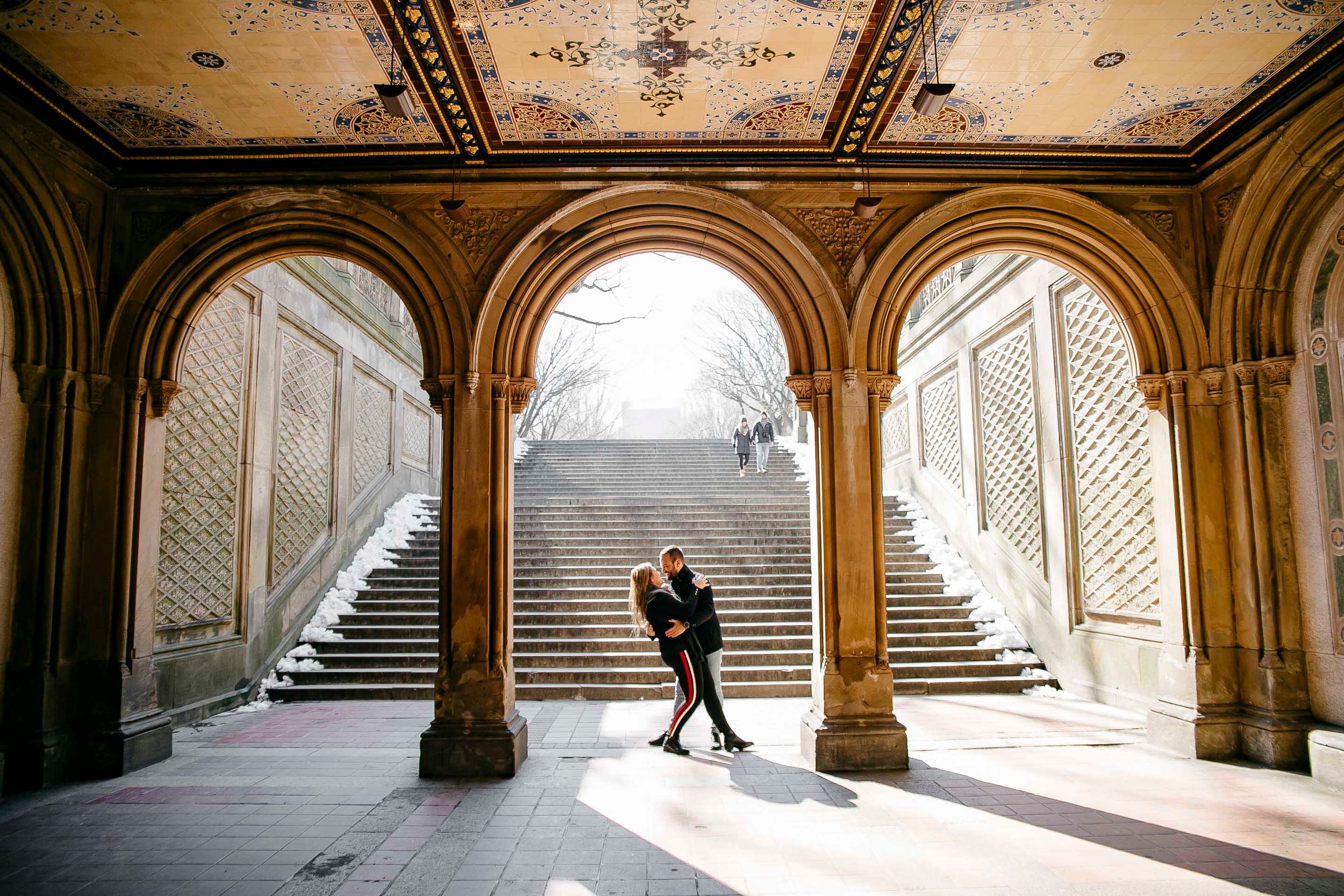 Silhouetted couple embracing in grand archway with stone steps.