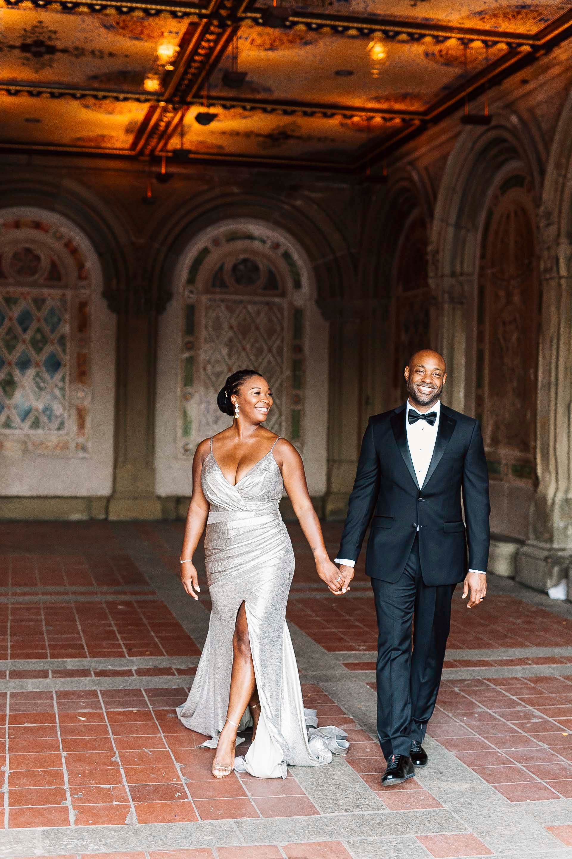Elegant couple in formal attire walking through ornate historic venue.
