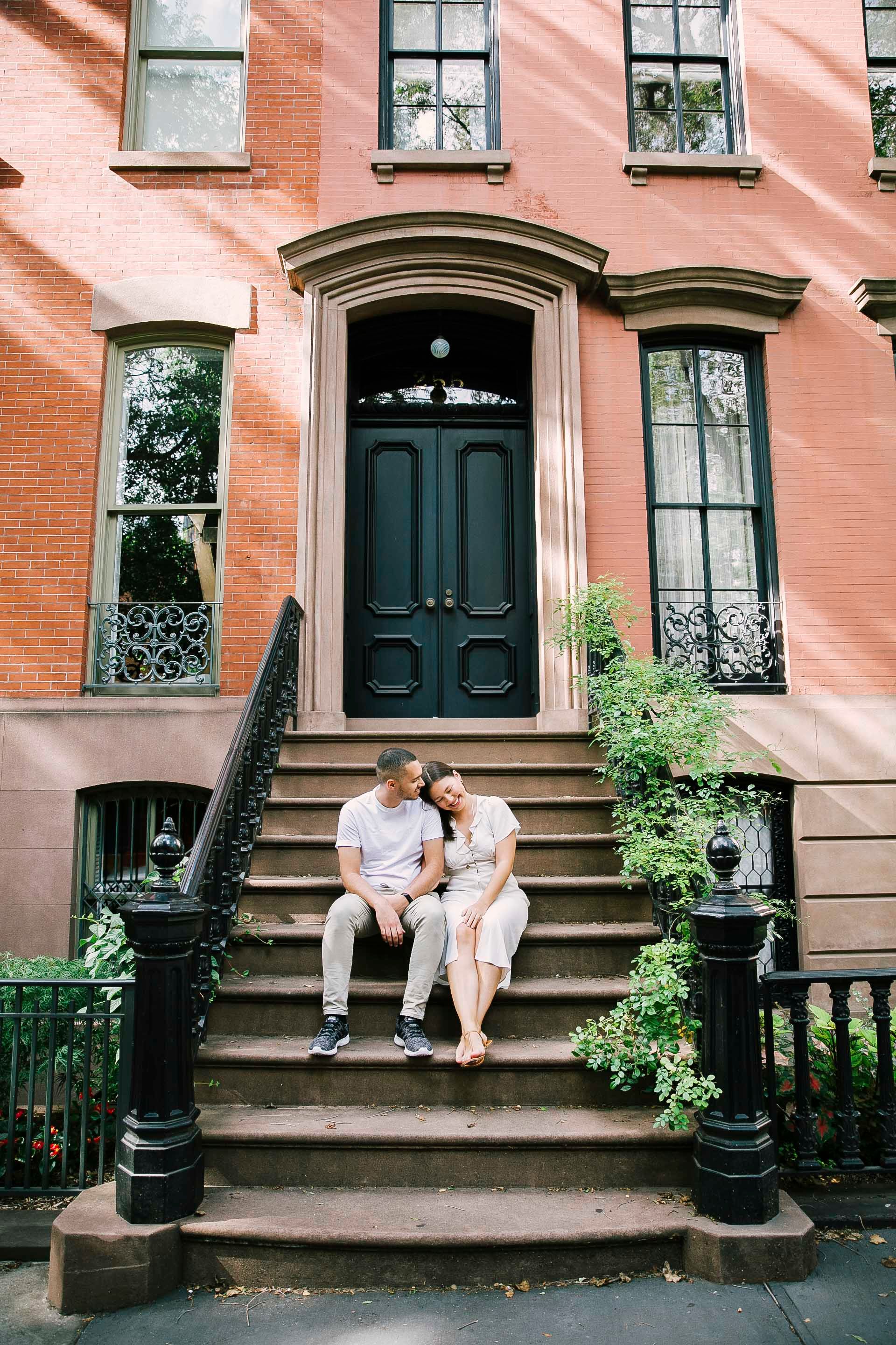 Couple sitting together on brownstone steps in historic New York neighborhood.