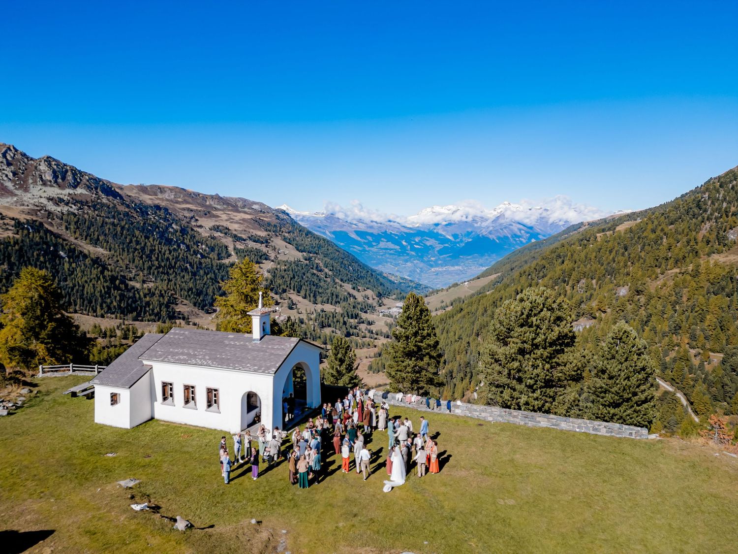 Panoramic view of turquoise alpine lake surrounded by snow-capped mountains in Switzerland with people enjoying scenery.