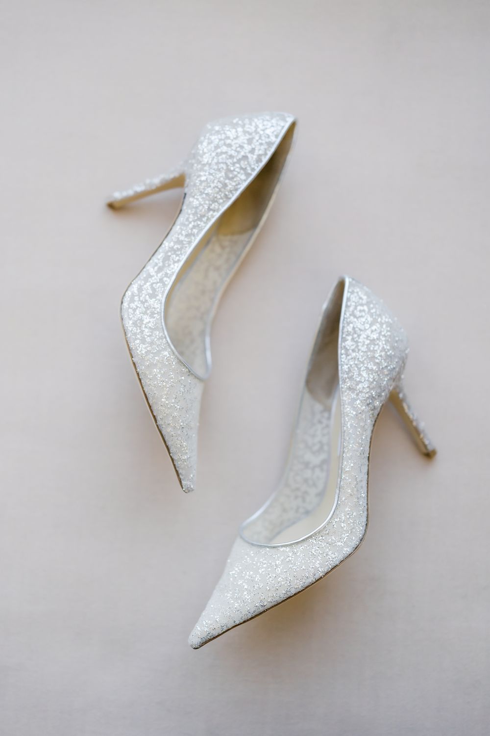 Sparkling white glitter pointed-toe stiletto wedding heels displayed on a neutral background.