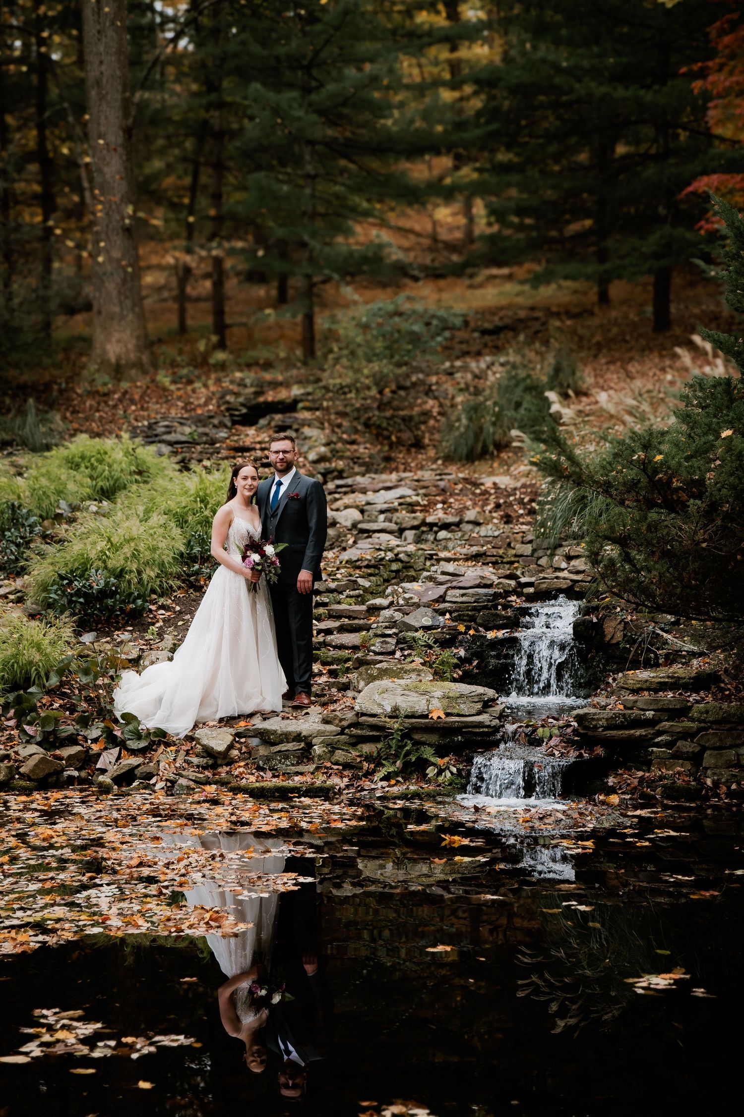 Bride and groom sharing a romantic kiss under a flowing white wedding veil outdoors.
