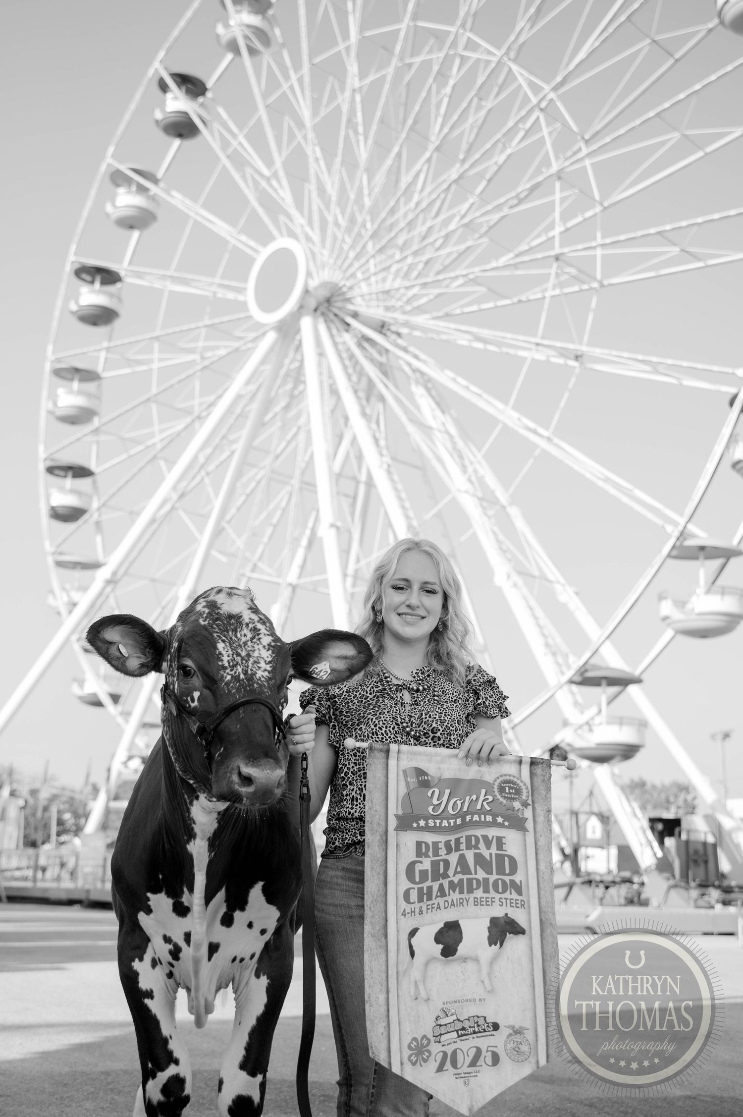 Girl poses with Holstein cow and Reserve Grand Champion sign at York State Fair with Ferris wheel backdrop.