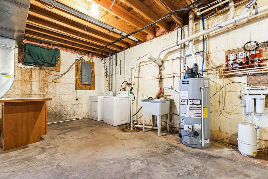Unfinished basement utility room with washer, dryer, water heater, and exposed pipes.