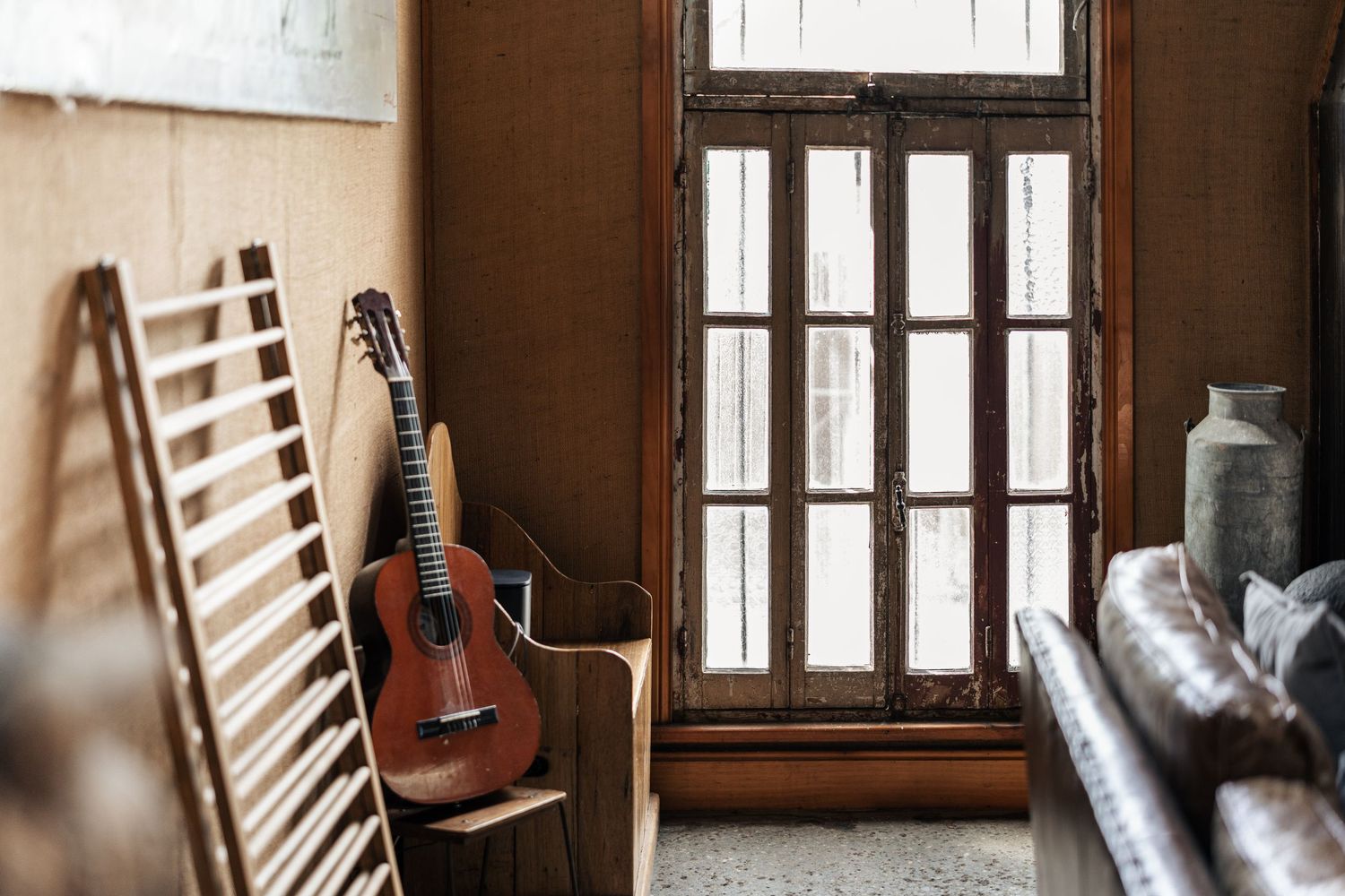 Acoustic guitar leaning against a wall beside a rustic wooden window with vintage decor.

The Barn