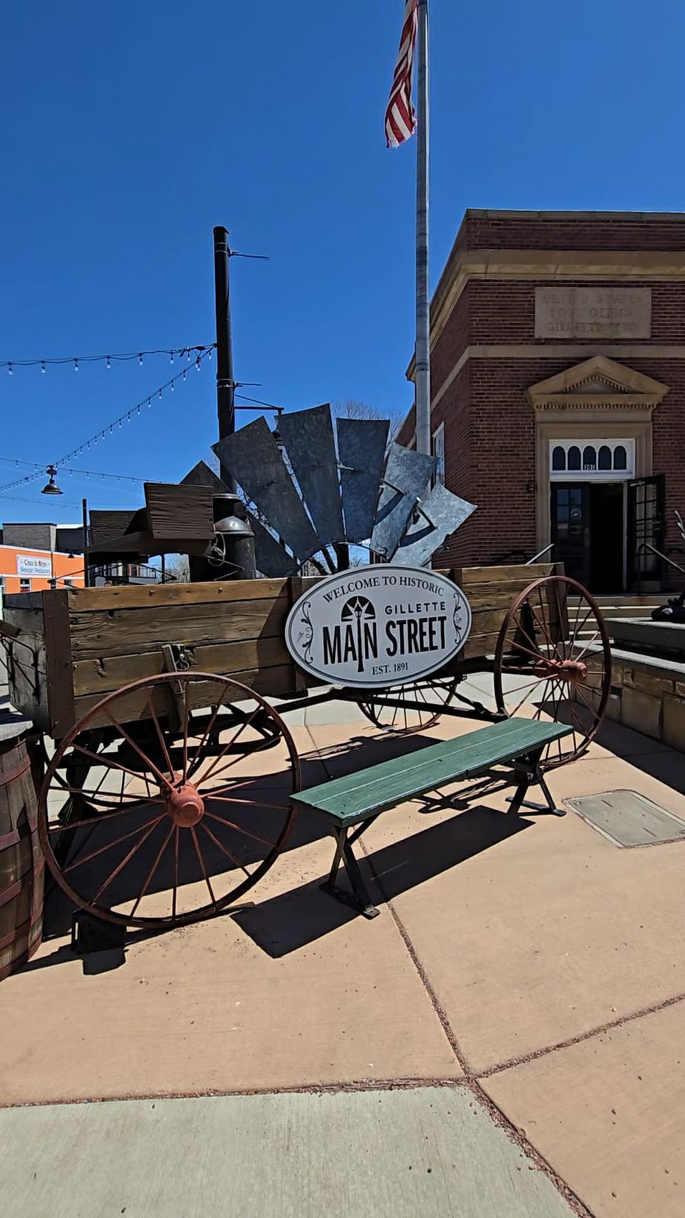 Vintage wooden wagon with windmill decor and Welcome to Historic Main Street sign on a sunny day in Gillette.