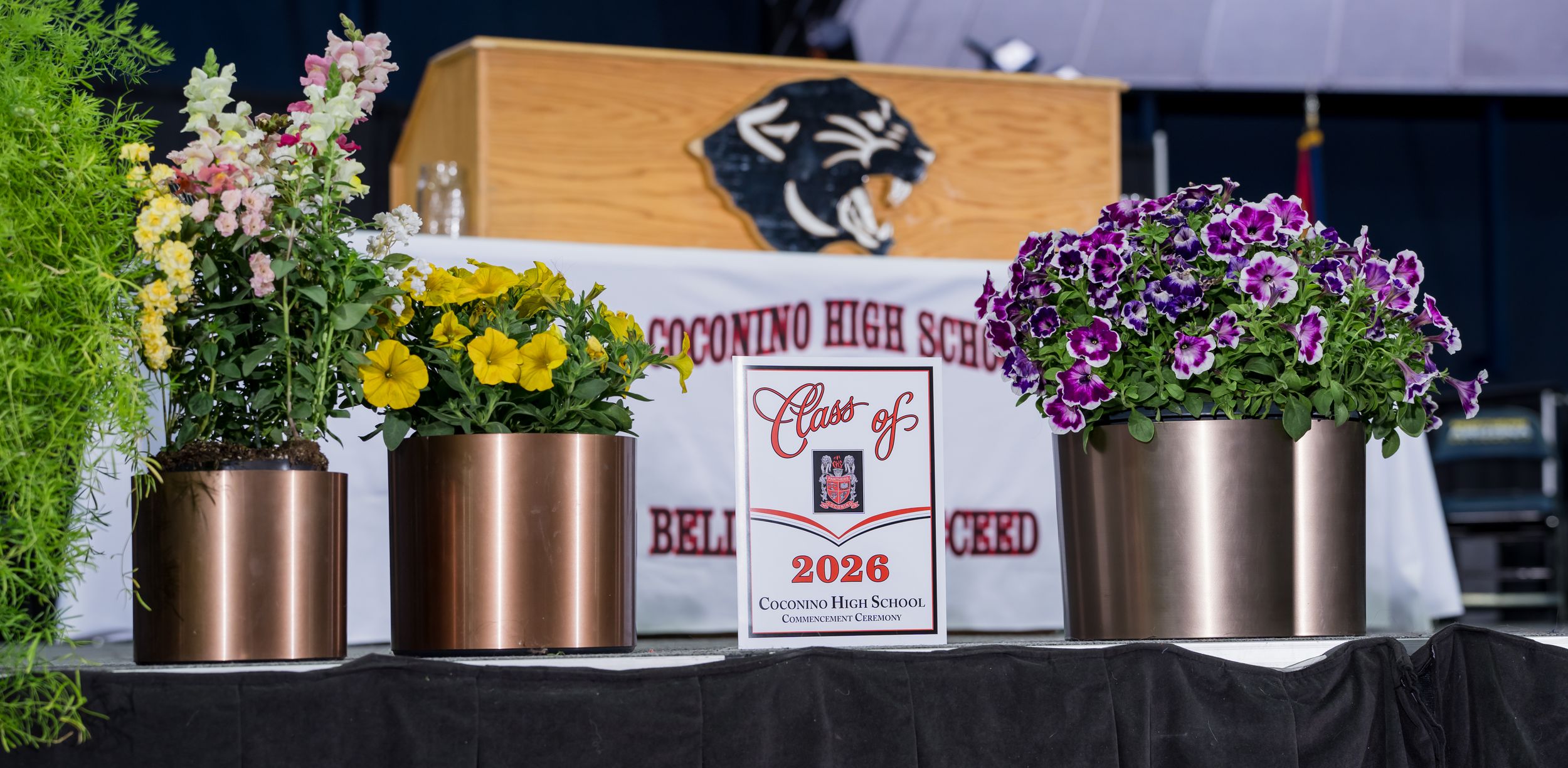 The Class of 2026 CHS Graduation program stands next to a flower arrangement on the commencement stage.