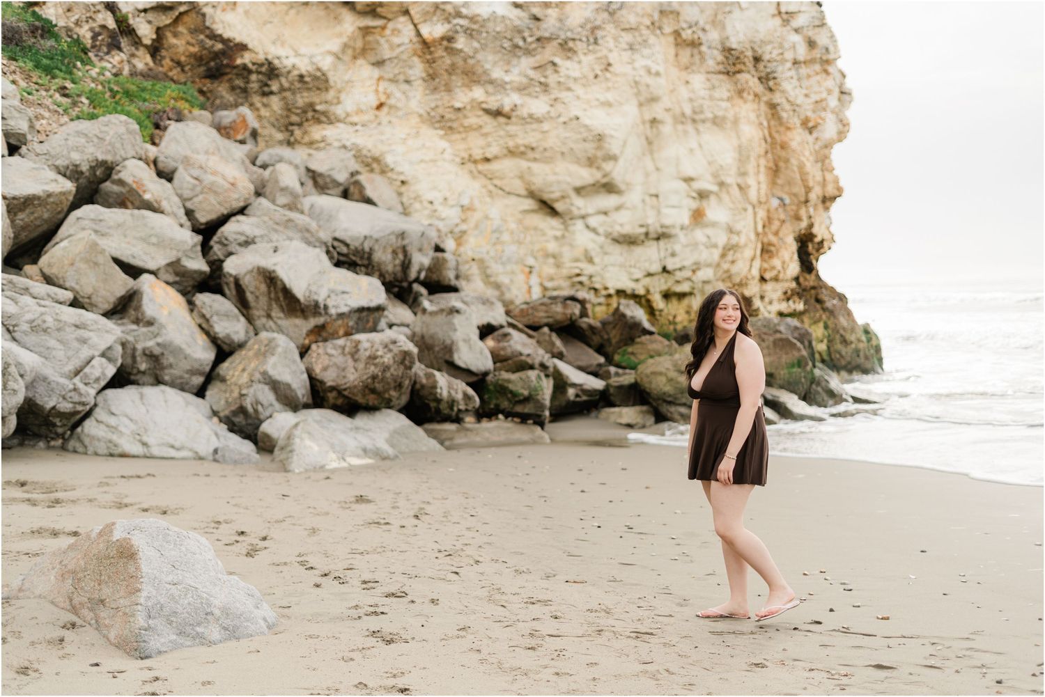 Senior photos in Avila Beach on a cloudy morning showcasing a senior girl walking along the shoreline.