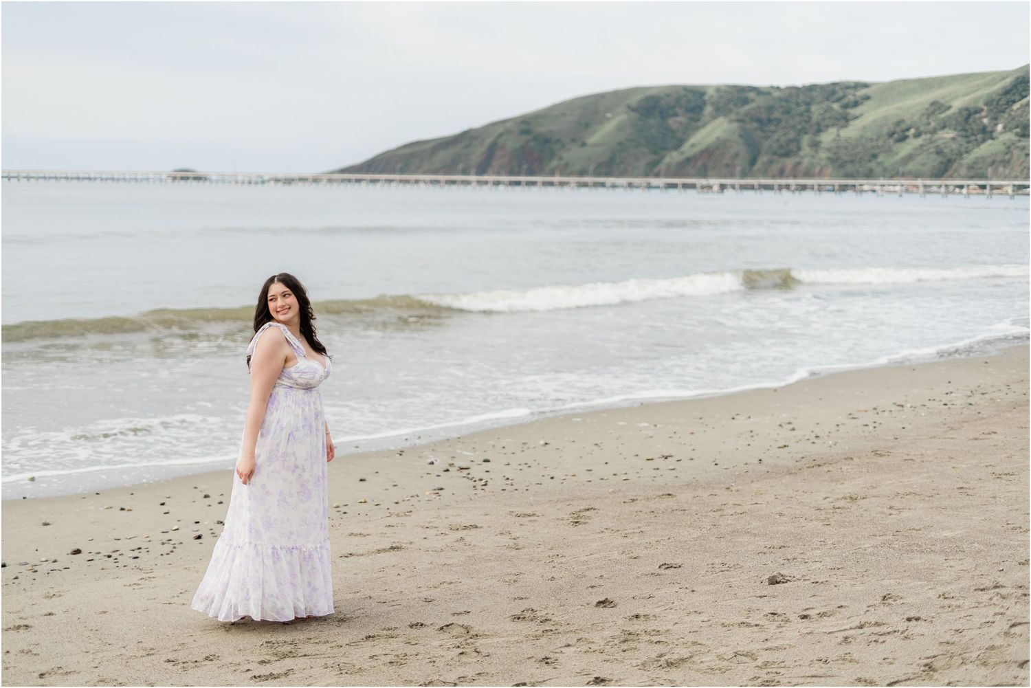 San Luis High senior photographer. Senior in a purple dress overlooking the ocean during a cloudy morning at Avila Beach.