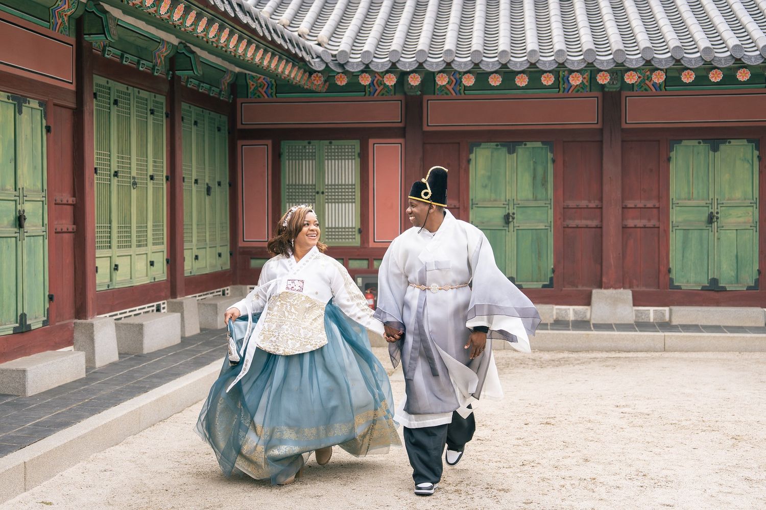 Couple in traditional Korean hanbok attire walking through a historic palace courtyard in Seoul, South Korea.