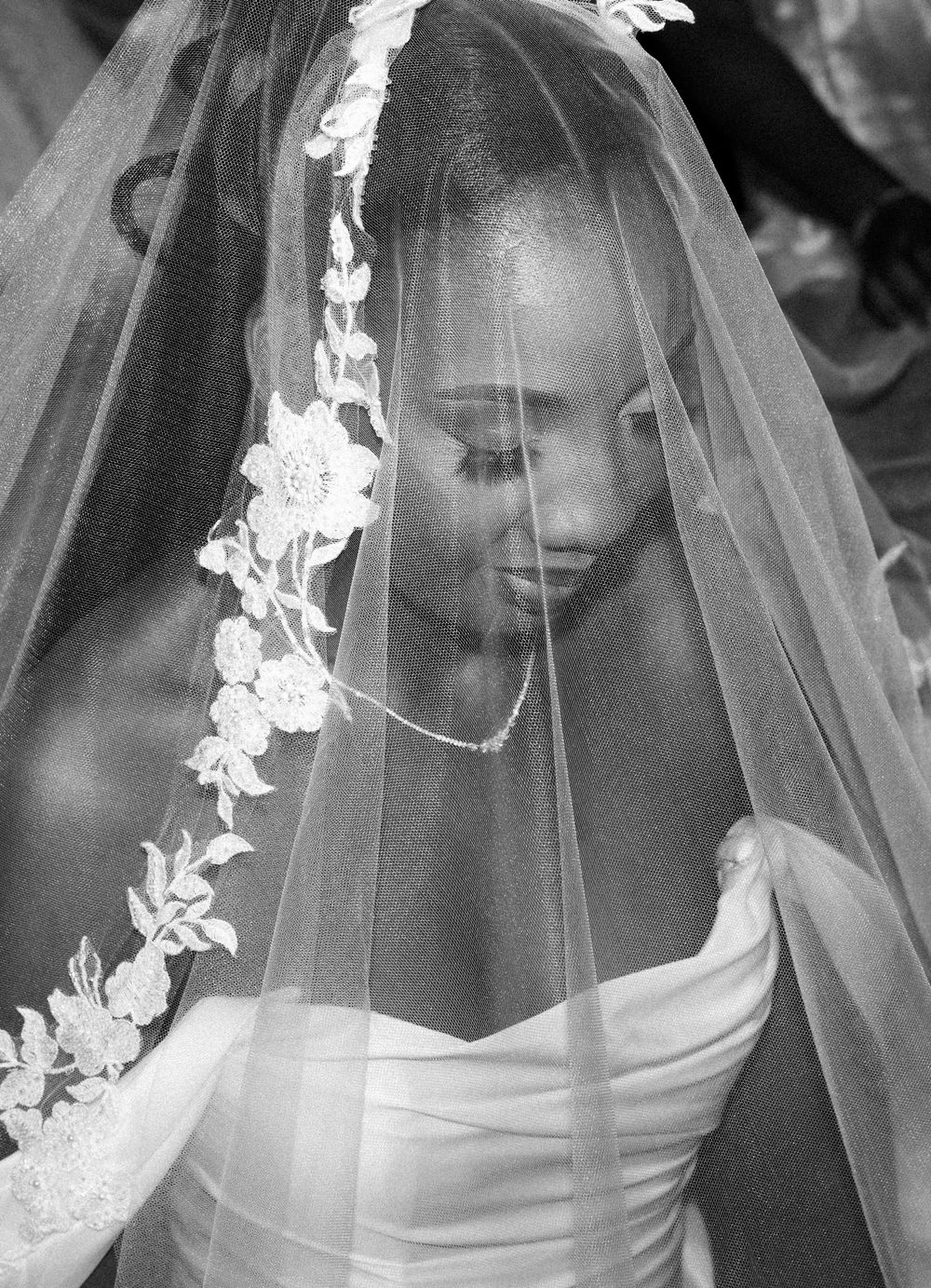 A black and white wedding photo series showing a bride in a veil with delicate floral lace details.