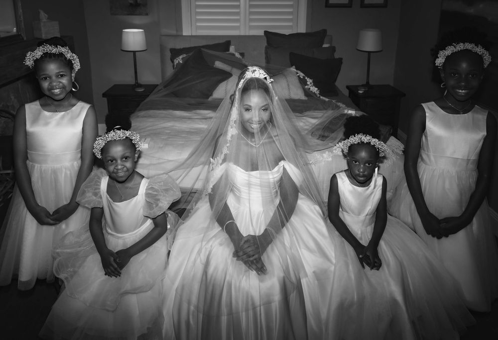 A group of children in white dresses and formal attire pose together in a black and white photograph.