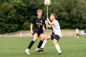 Soccer players compete for possession of the ball during an intense match on a grass field.