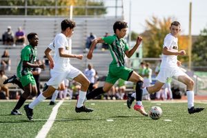 Soccer players in white and green jerseys compete for the ball during an intense match.