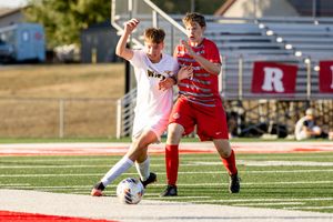 Soccer players compete for possession of the ball during an intense match on a sunny afternoon.