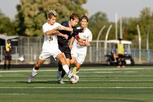 Soccer players battle for possession of the ball during an intense match on an artificial turf field.