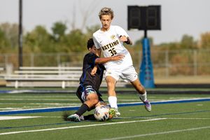 Soccer player sliding across blue turf field during competitive match.