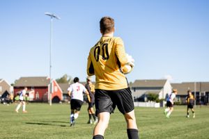 Young soccer players in yellow and white uniforms practice on a sunny field during a youth sports match.