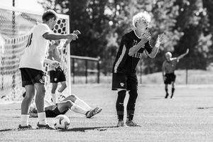 Youth soccer players compete for the ball during an intense match on an outdoor field.