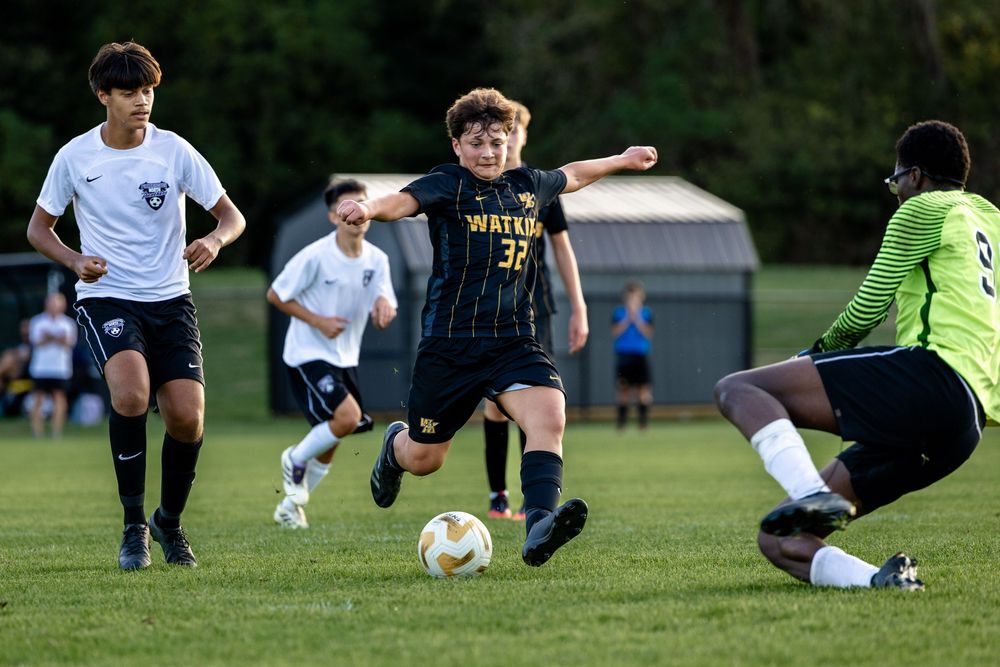 Soccer players stretch and warm up together on a grassy field during practice session.