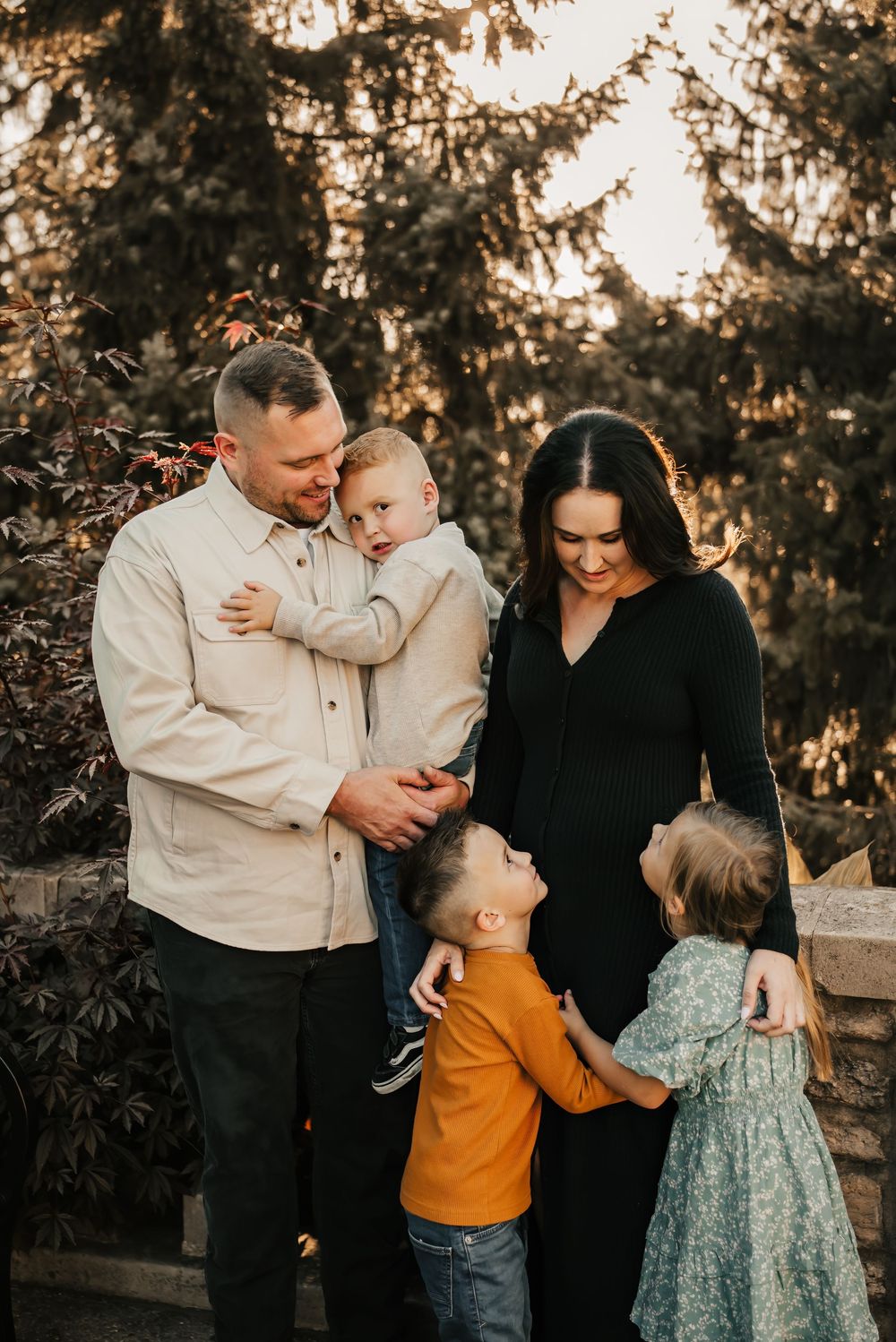 Family sitting on a blanket surrounded by golden foliage during fall mini photos.