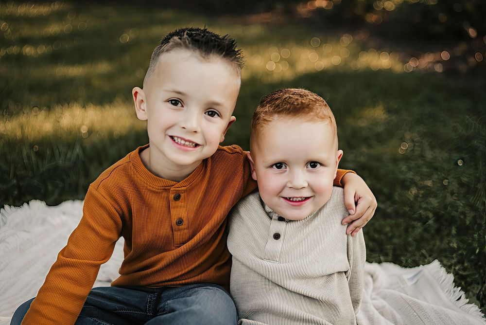Family sitting on a blanket surrounded by golden foliage during fall mini photos.