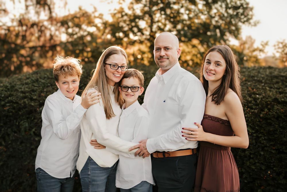 Family laughing together in front of vibrant orange and red trees at Ault Park.