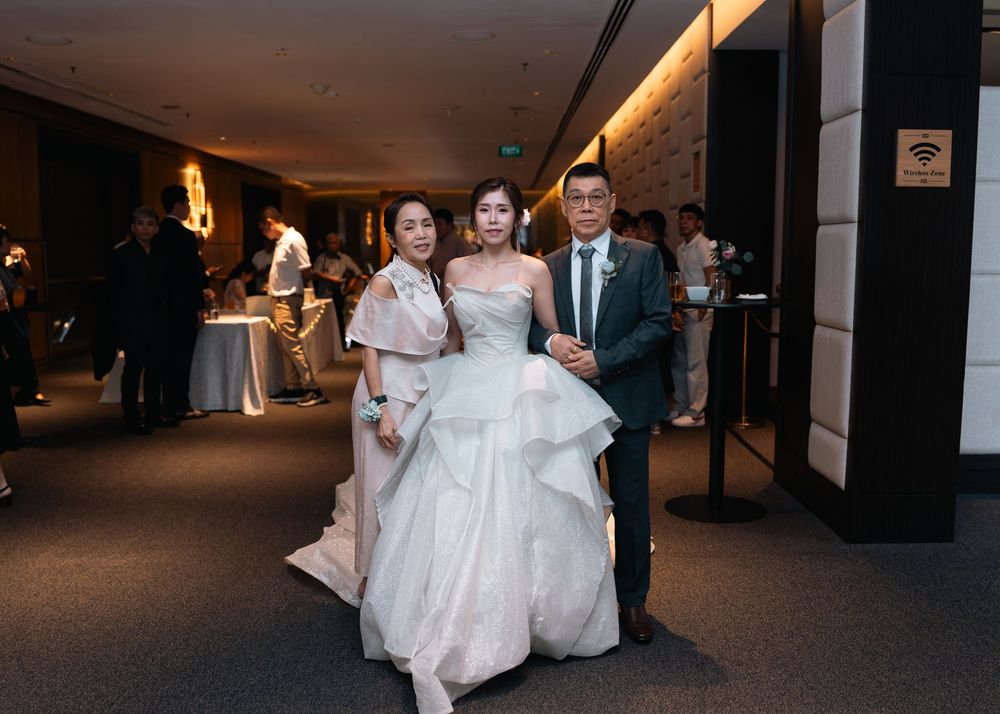 A wedding party walks down a dimly lit hallway in formal attire.