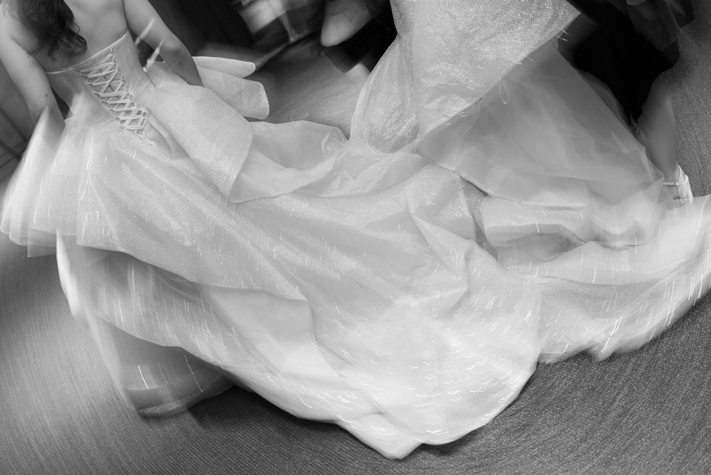 A flowing white wedding dress billows gracefully across a dark floor.
