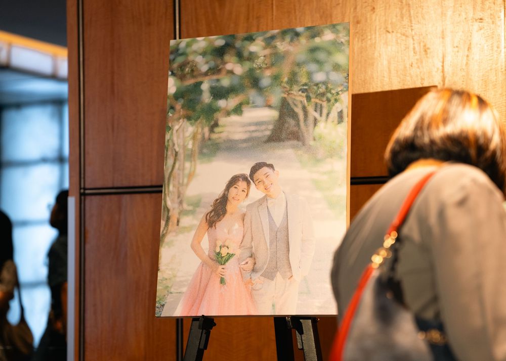 Wedding photographs displayed on wooden walls show romantic moments between couples at sunset.