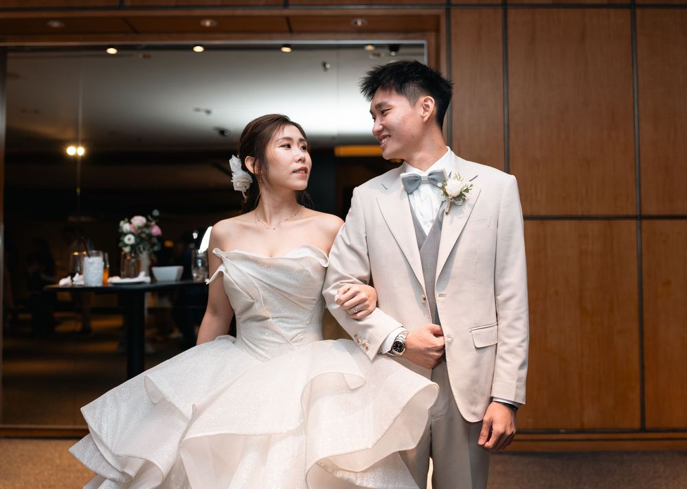 Wedding party members pose in elegant formal wear against wood-paneled walls.