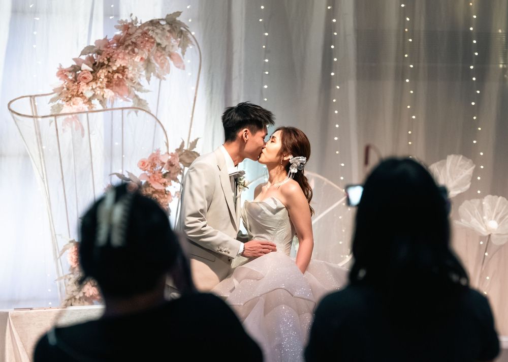 A couple shares a romantic dance moment at their wedding reception while guests watch in the background.