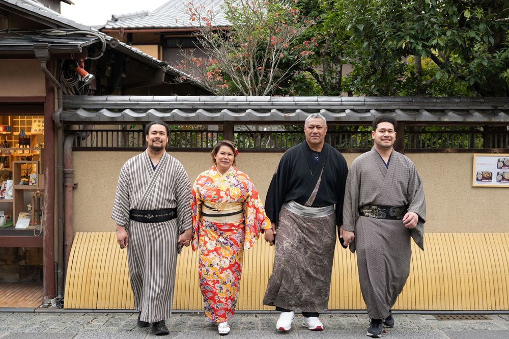 Family of four wearing traditional Japanese kimono and yukata posing on a Kyoto street.