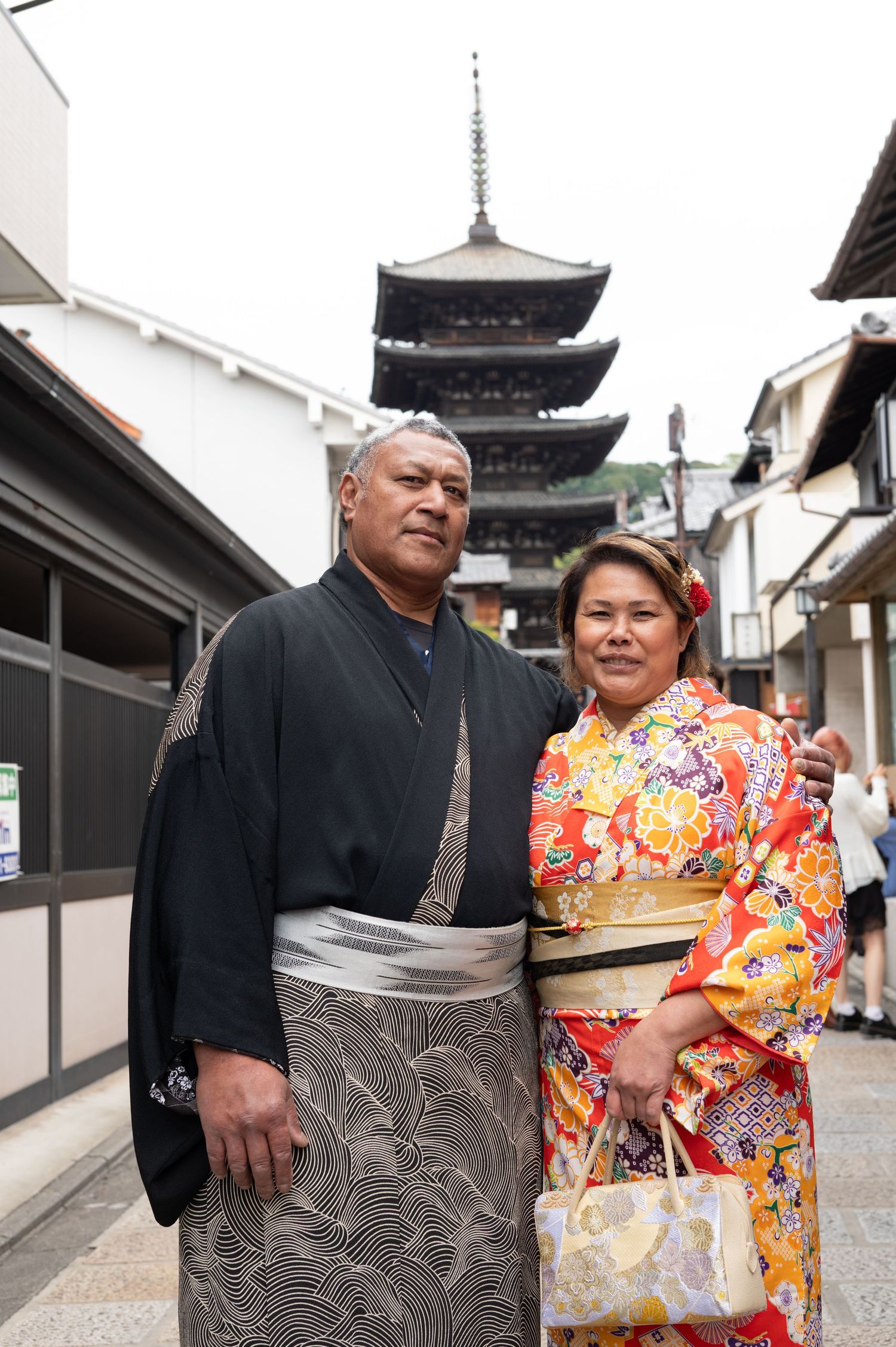 Couple posing in traditional Japanese kimono and hakama with pagoda backdrop.