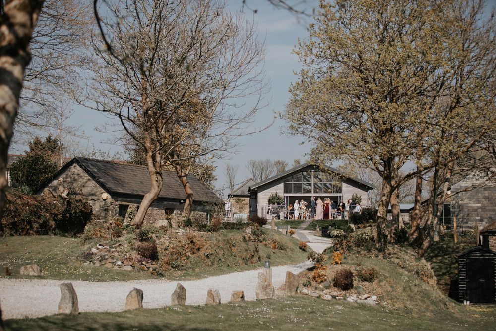 Rustic countryside wedding venue with stone buildings and bare trees on a sunny spring day.