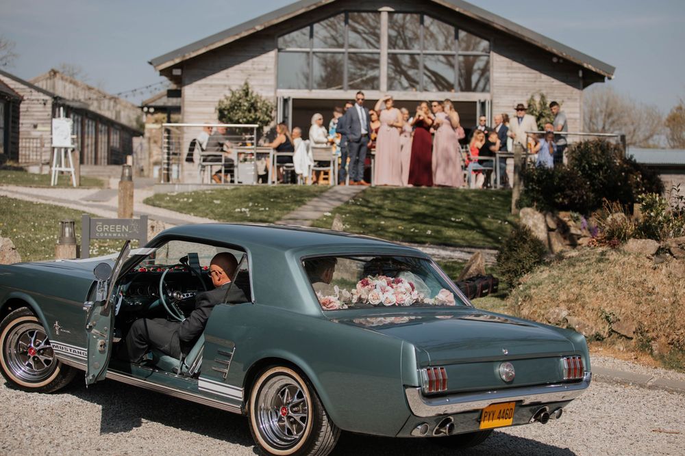 Classic green Ford Mustang vintage wedding car parked outside a rustic barn wedding venue.