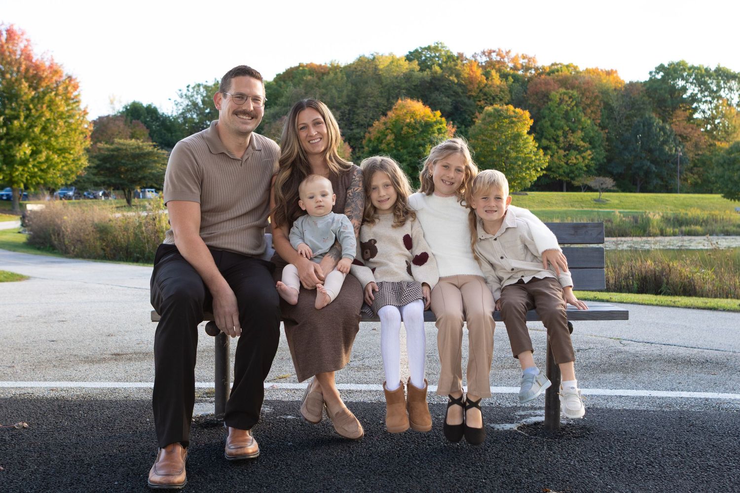 A casual family portrait session outdoors during golden hour at a park.