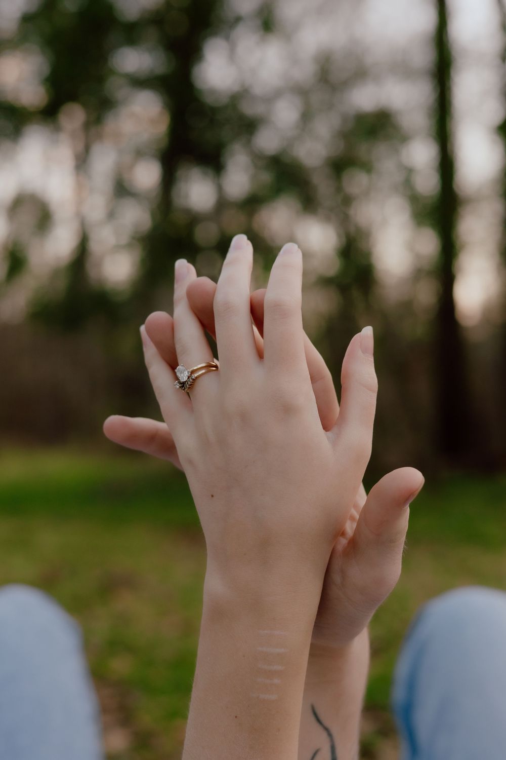 Small hands reach up towards the sky in a natural outdoor setting with trees in the background.