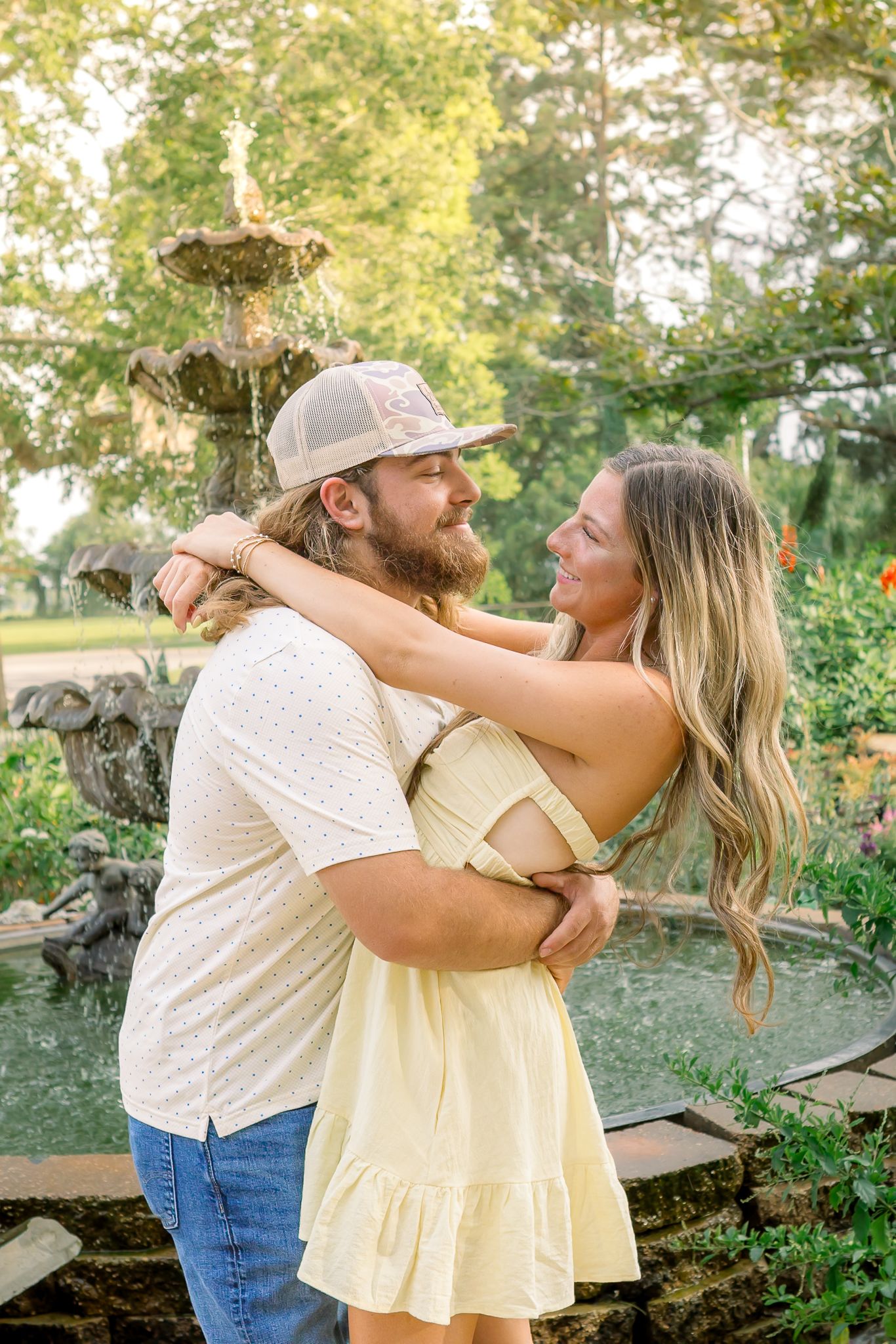 A romantic couple sharing an intimate moment at sunset in a field with golden light filtering through trees.