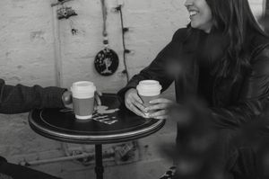 A black and white photo of people enjoying drinks and conversation at a bar or restaurant.